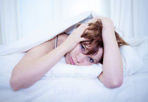 A woman laying in bed under the covers.