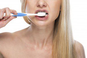 Woman brushing her teeth with toothbrush.