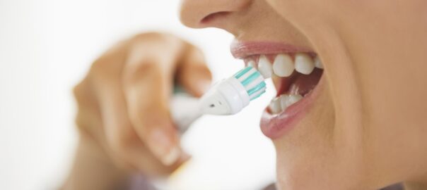 Person brushing teeth with electric toothbrush.