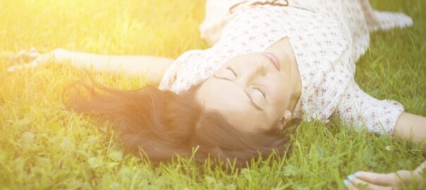 Woman lying in grass, enjoying sunlight.