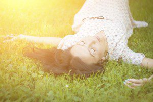 Woman lying in grass, sunlight shining.