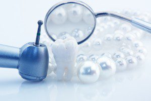 Dental tools and a tooth surrounded by pearls.