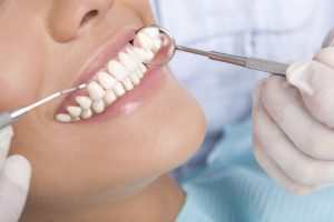 Dental check-up with tools and patient.