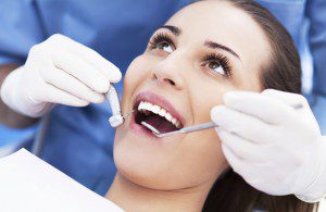 A woman getting her teeth cleaned by dentist.