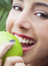 Smiling woman holding a green apple.