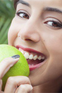 A woman is eating an apple outside